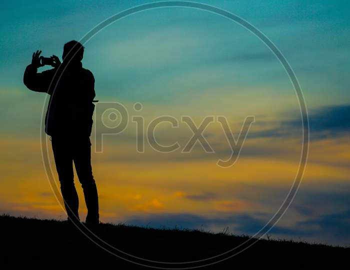 Silhouette Of Men Standing On Sunset Hills