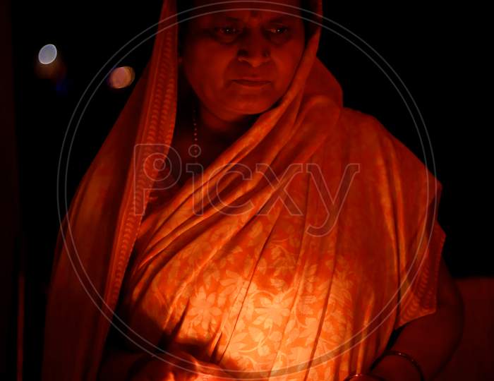 Portrait of an India woman holding a diwali diya in a dish in the dark of the night.