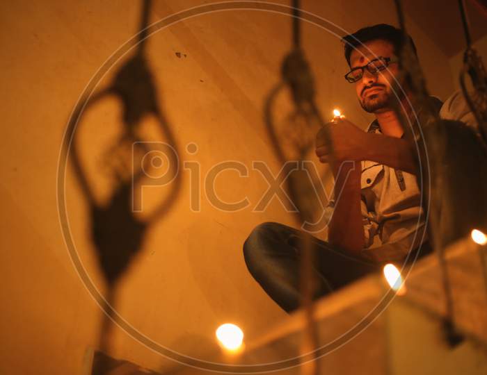 A man sitting on the top of a staircase looking at diwali candle in his hands.