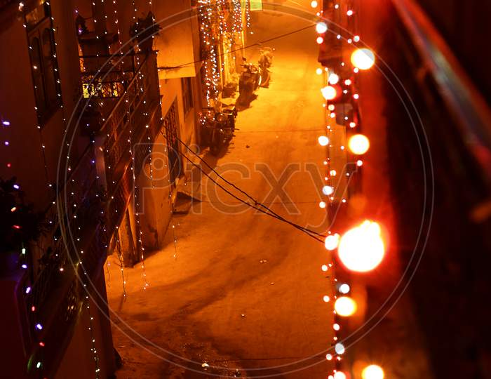 A balcony view of a deserted street lit up by diwali lights.