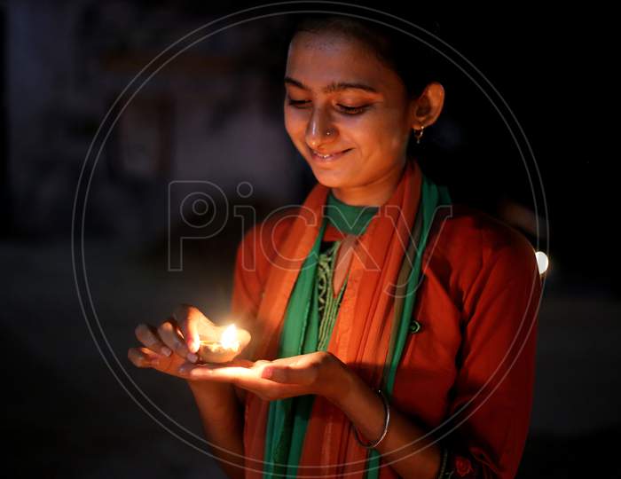 An india girl holding diwali diya with a smile on her face.