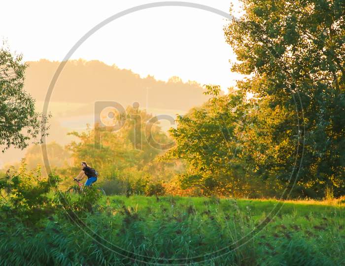 Regensburg, Germany- September 08, 2021:  People Are Riding The Bike On A Rural Road At Sunset Along Danube River In Regensburg, Germany, Europe.
