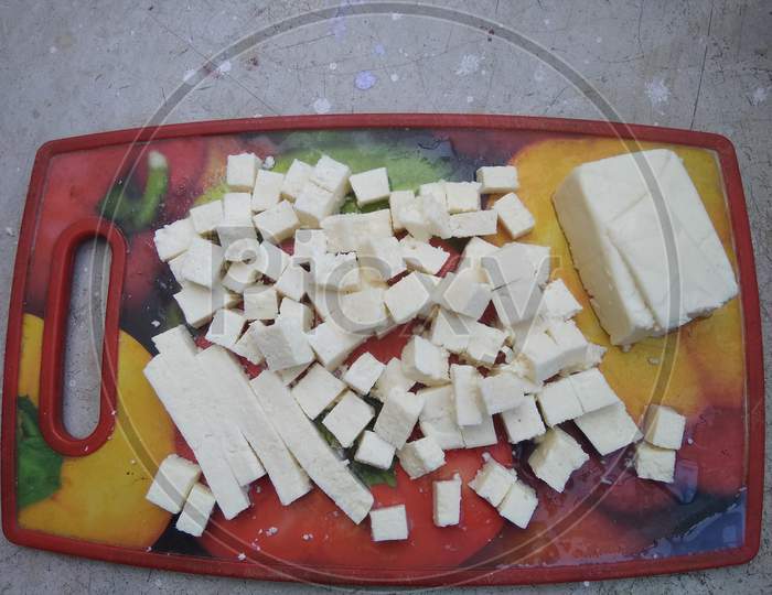 Paneer, cheese and cheese cubes with colorful choping board