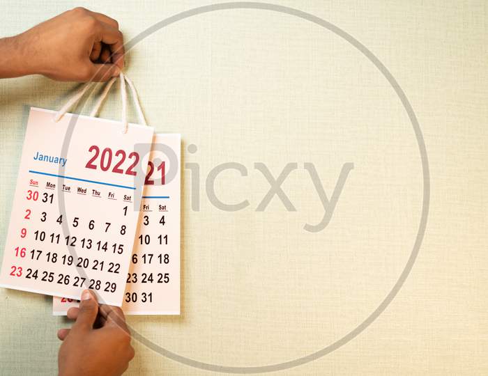 Close Up Shot Of Hand Replacing 2021 Old Calendar From 2022 New Year Calendar On Wall - Concept Of End Of 2021 Or Beginning Of New Year 2022