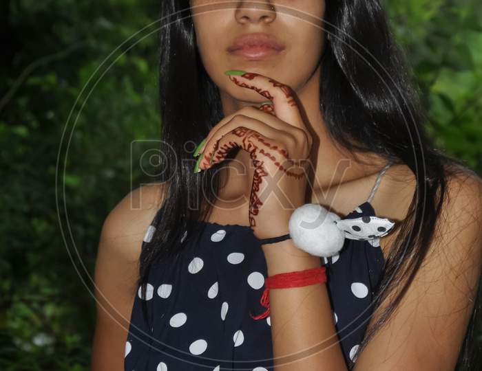 Portrait of a beautiful North Indian young girl looking at the camera and posing with one hand on the chin and the other on the hip
