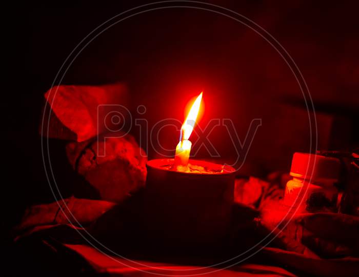 A photo of a vanilla scented candle red lighting in the dark room with bokeh light in the background