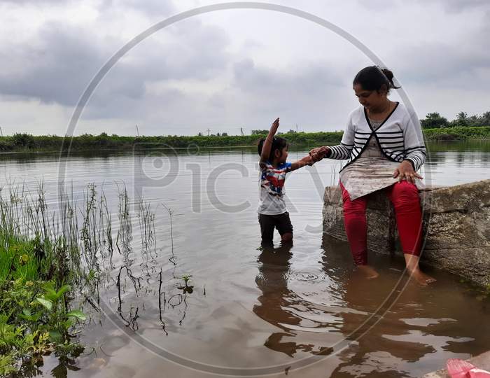 Closeup Of Beautiful Indian Kid And Mother Playing In A Pond Of Village At Bevoor, Ramanagar