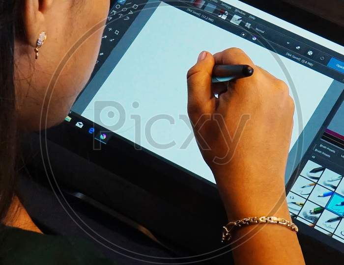 Close-Up View Of Indian Woman Hand Holding Pen And Sketching On Drawing Pad