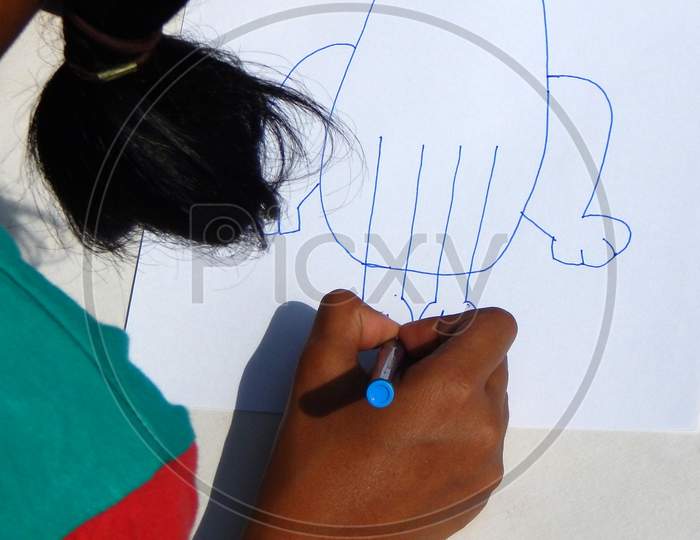 Child Drawing With Color Pencil On White Paper In Outdoors