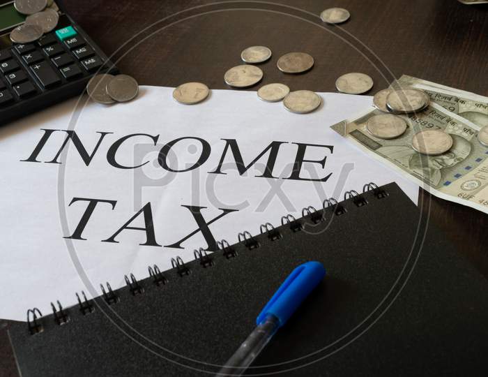 Mumbai, India - 19 October 2021, Picture of printed paper on which Income tax is written along with calculator, Indian currency, diary and a pen.