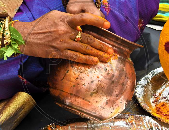 Indian Hindu Woman Decorating The Vessel, With Turmeric And Vermilion, To Offer Food To Goddess Mahan Kali  As Bonam