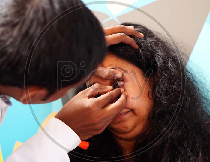 Close-Up View Of Indian Male Doctor Checking Woman Patient Eye To Insert Contact Lens In A Clinic
