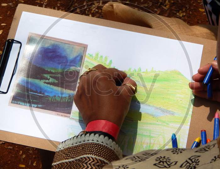 Indian Child Painting With Crayons  In Outdoors