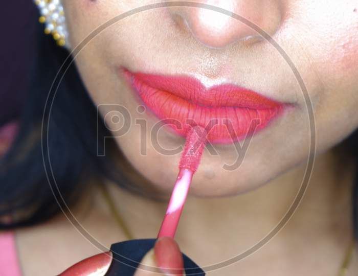 Close Up Image Of Girl Putting Red Color Lipstick On Lips.