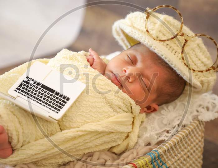 Cute Girl Covered With Towel And Stylish Cap Sleeping In Basket Baby Toy Laptop And Sunglasses