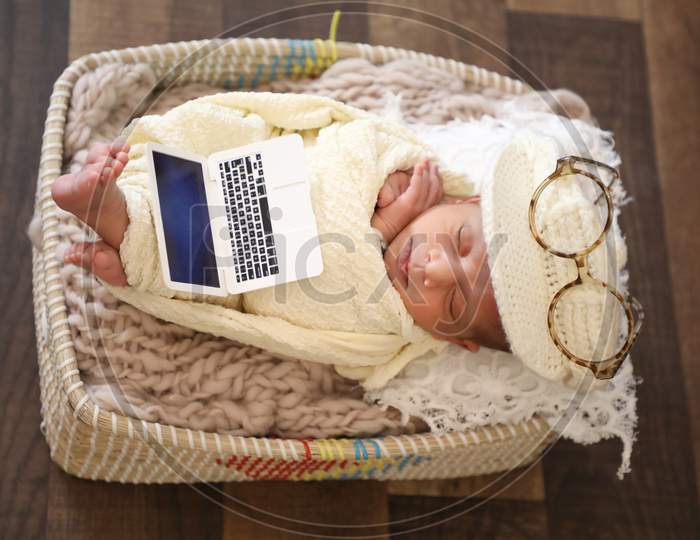 Cute Girl Covered With Towel And Stylish Cap Sleeping In Basket Baby Toy Laptop And Sunglasses