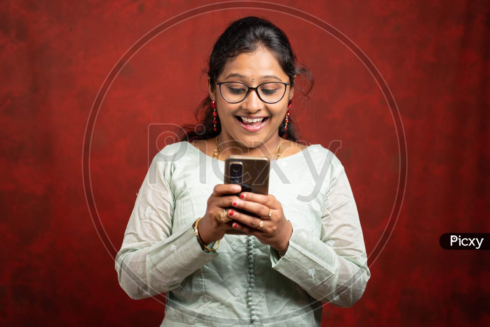 Portrait Shot Of Surprised Young Indian Woman By Seeing Online Sales And Offers On Mobile Phone During Festival - Concept E-Commerce Discounted Shopping.