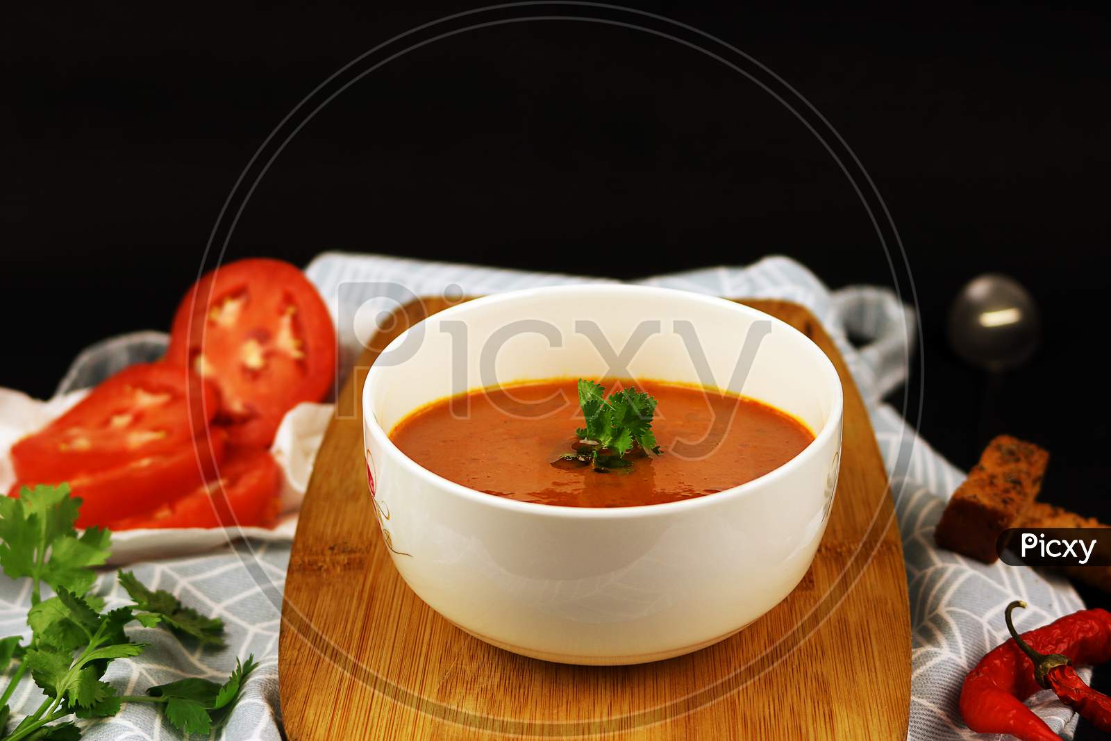 Fresh Tomato Soup with garnishing in a white bowl. Vegan soup with tomato and chilly.