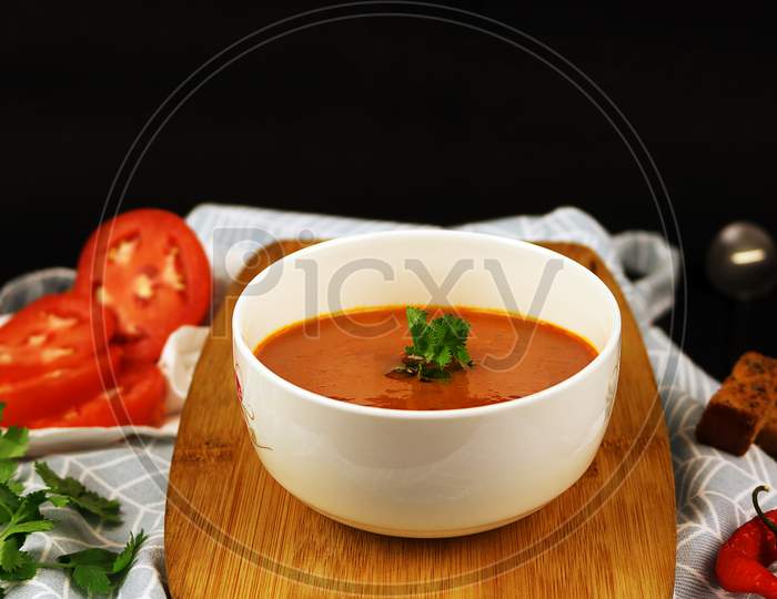 Fresh Tomato Soup with garnishing in a white bowl. Vegan soup with tomato and chilly.