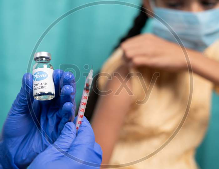 Maski, India - October 26, 2021 : Selective Focus On Vaccine Bottle - Kid With Medical Face Mask Getting Vaccinated Pfizer'S Covid-19 Or Coronavirus Children Vaccine At Hospital.