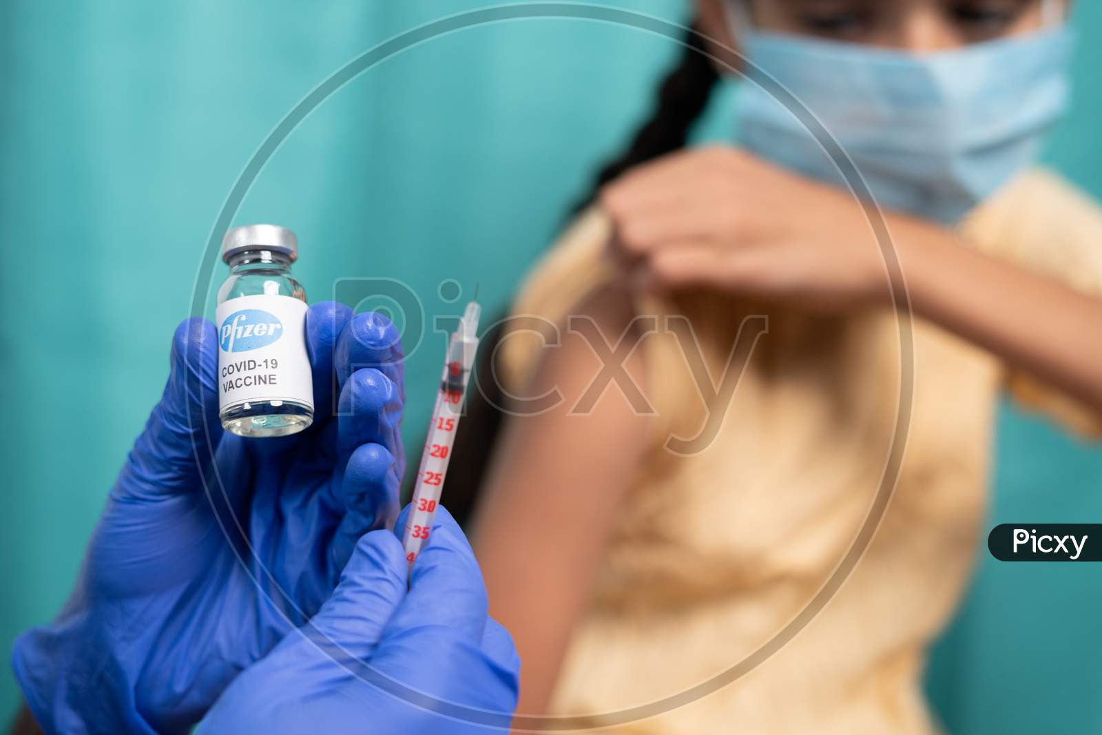 Maski, India - October 26, 2021 : Selective Focus On Vaccine Bottle - Kid With Medical Face Mask Getting Vaccinated Pfizer'S Covid-19 Or Coronavirus Children Vaccine At Hospital.