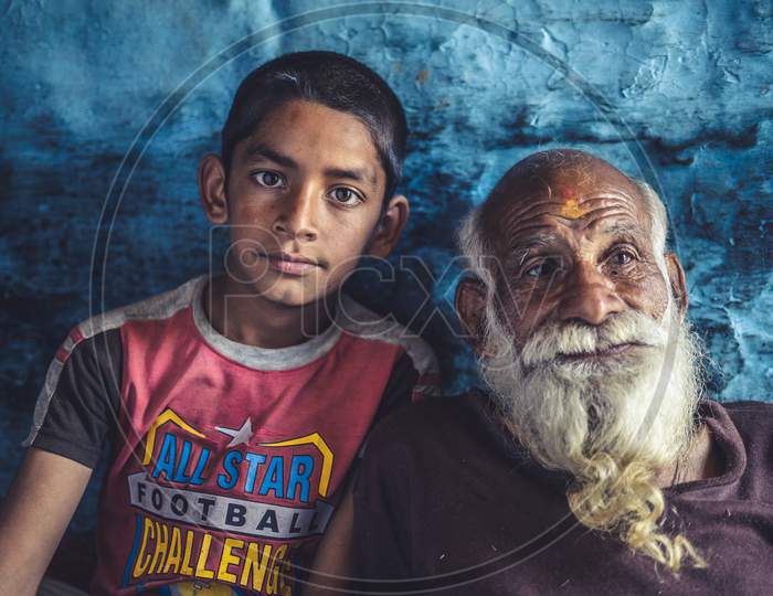 Portrait Of A Kid Sitting With His Grand Father. Indian Kid Posing Towards The Camera While Sitting With His Grandfather.