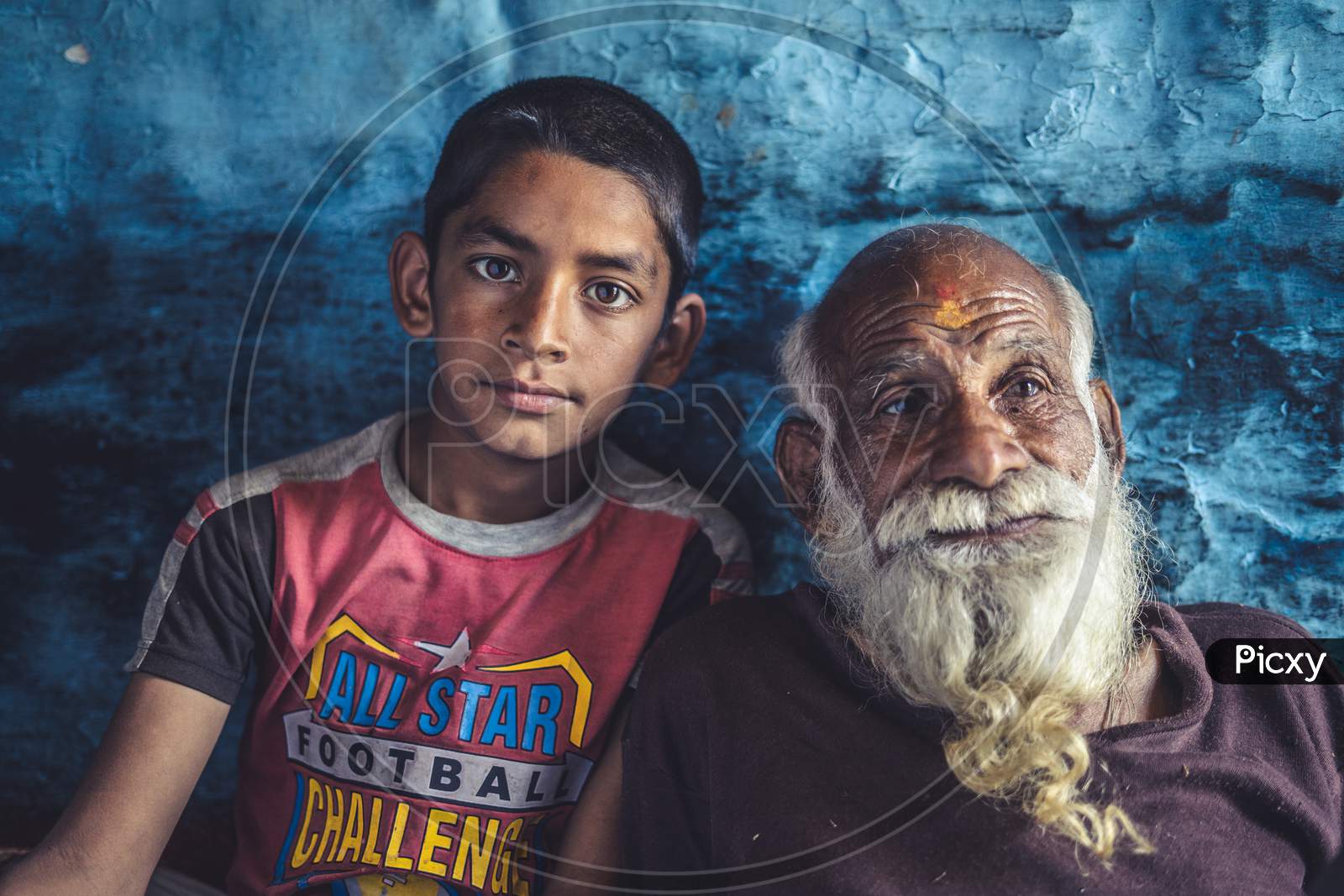 Portrait Of A Kid Sitting With His Grand Father. Indian Kid Posing Towards The Camera While Sitting With His Grandfather.