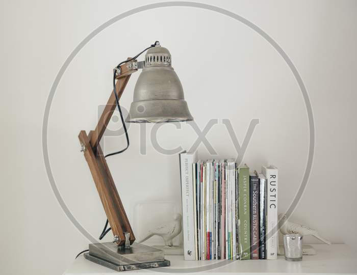 Silver Lamp On A White Table Next To Books