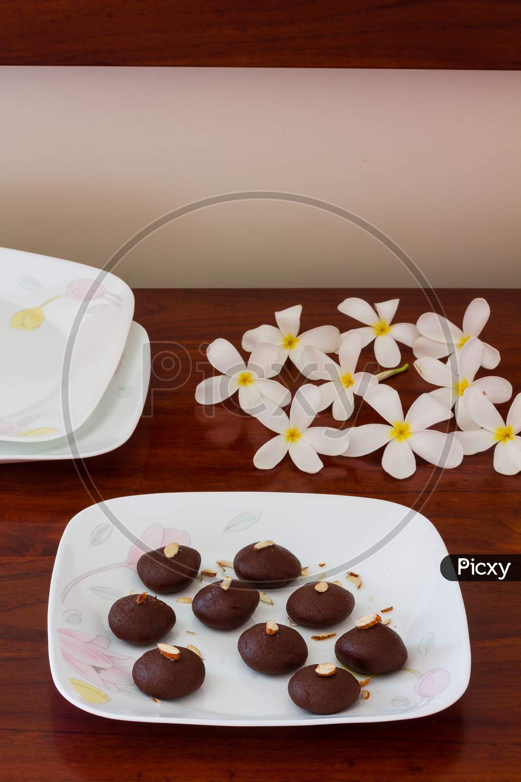 Top view of dark chocolate truffle or cocoa balls or pralines or candies,isolated on dark wooden background with Frangipani flowers.