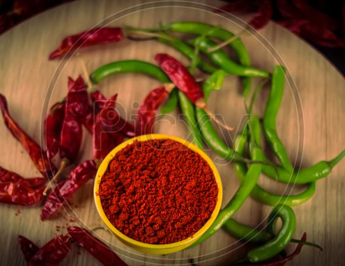 There Are Dried Chillies And Blue And Red Chillies On The Table With Chili Powder Is Falling From Above, Yellow Bowl In Chili Pepper Powder Close Up View