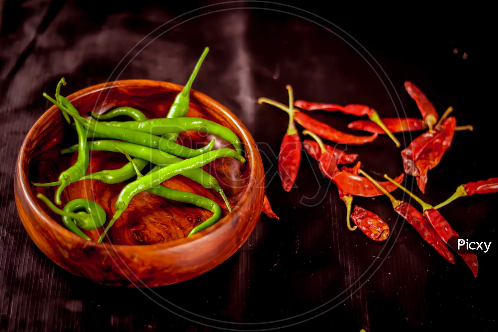 The Green Chillies Are Falling Into The Wooden Bowl,Fresh Green Chili In Wooden Bowl With Black Background,Green Pepper Or Chili