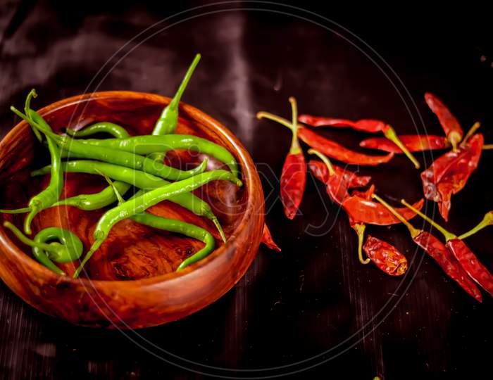The Green Chillies Are Falling Into The Wooden Bowl,Fresh Green Chili In Wooden Bowl With Black Background,Green Pepper Or Chili
