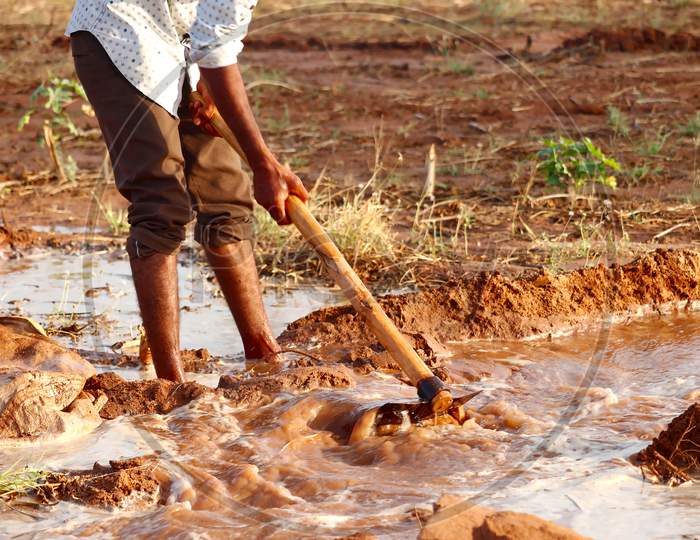 Man Working In Garden Between Beds With Hoe In Hands,Young Indian Farmer Water The Field,Selective Focus,Indian Farmer Working In Farm With Hoe,