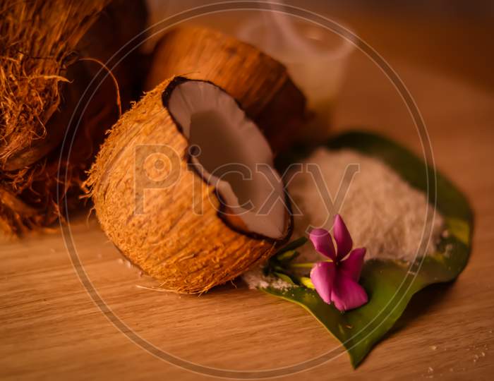 Coconut With Fresh Coco Milk And Powder On Wooden Table,Healthy Coconut Milk With Whole Nut,Coconut With Leaves And Flower,Cracked Coconut And Grated Coconut Flakes On Background.,Selective Focus On Subject,