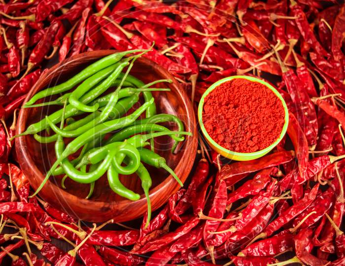 Red Chili Peppers Powder In Yellow Bowl In Wooden Spoon On Chili Peppers Background,Green Chili And Red Chilli,Spices And Bowl With Chilli Pepper On Wooden Background