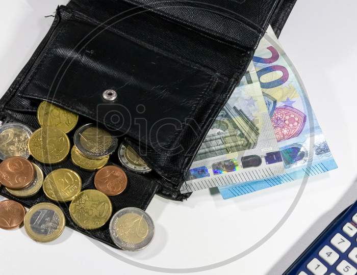 European money with black wallet on white desk as white background with different euro coins and euro bank notes with calculator for financial management and income business plans for tax calculation