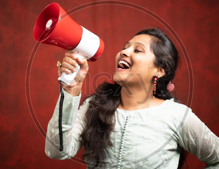 Young Indian Girl Announcing About Product Promotion Or Sales And Offers Using Megaphone.