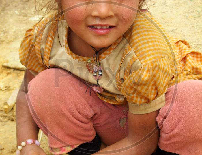 A beautiful Nepali girl playing with mud. Dirty hands. Rural life photo.