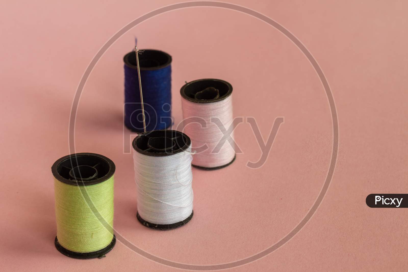 Spools With Colored Threads For Sewing. Elements Of A Sewing Workshop On A Neutral Pink Background.