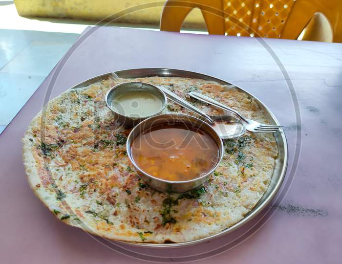 onion uttapam is south indian dish with coconut chutney, sambar