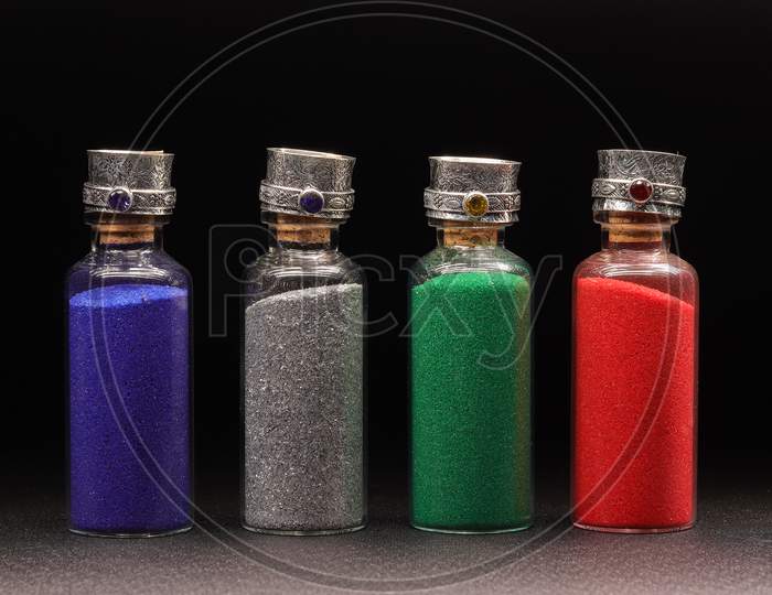 Colorful Glitter In Pots Over Black Background.