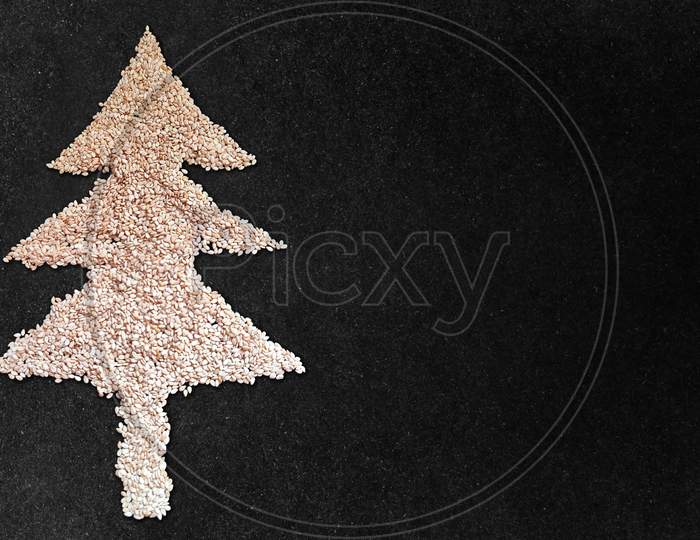 White Sesame Seed Christmas Tree Designed On Black Granite Texture Background With Blank Space. Top View.