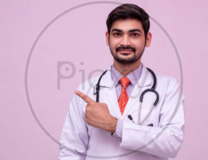 Young Doctor Showing Some Empty Space For Text From Hand On Isolated Background.
