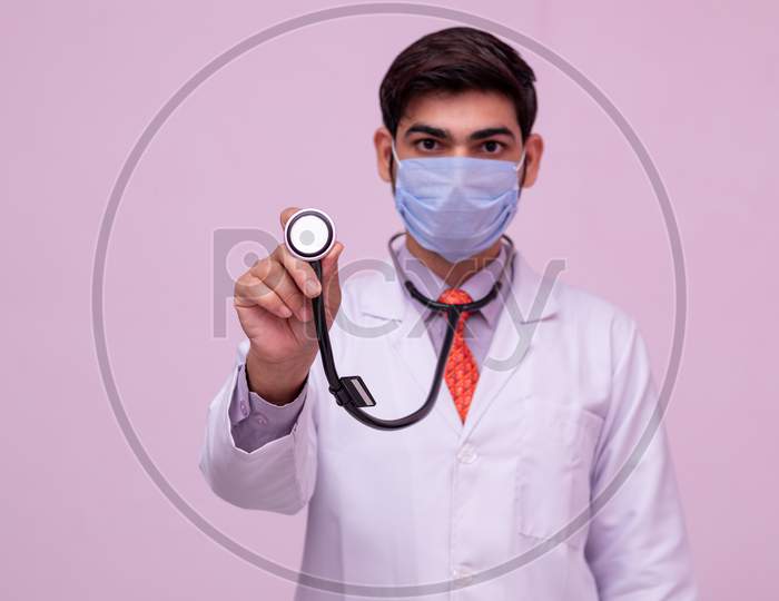 Doctor Wearing Medical Mask  Showing Stethoscope In Hand On Isolated Background.
