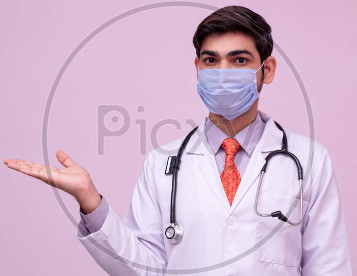 Young Doctor Wearing Mask Holding Something In Empty Hand Isolated Background.