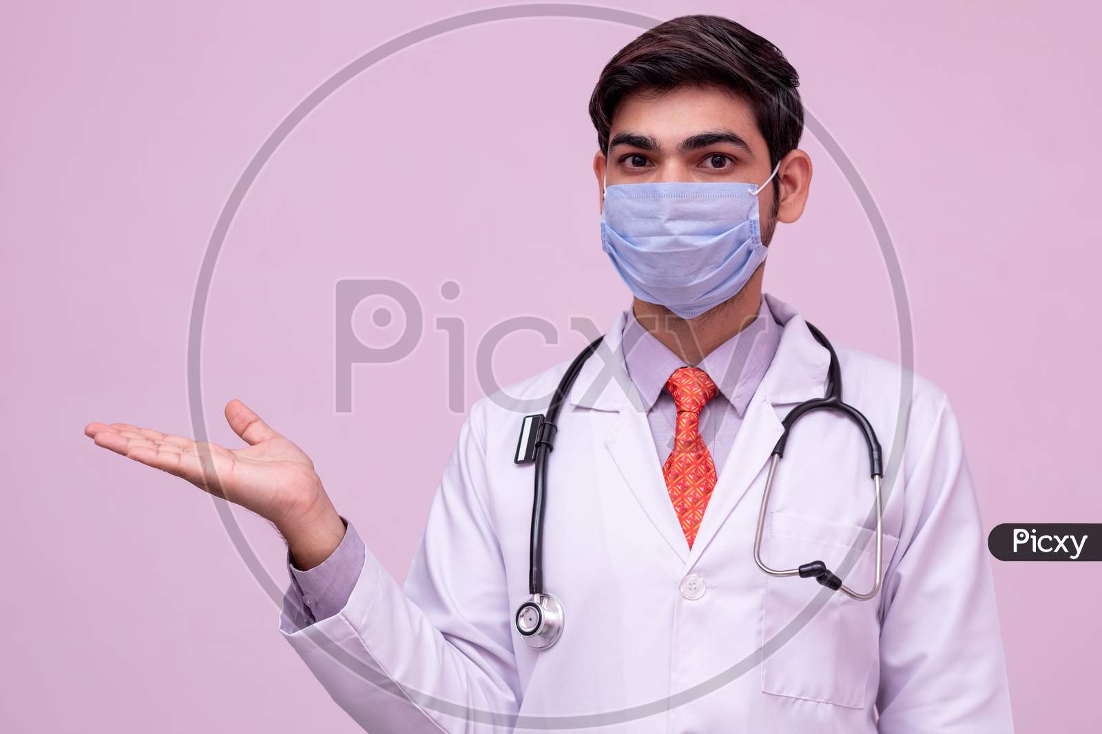 Young Doctor Wearing Mask Holding Something In Empty Hand Isolated Background.