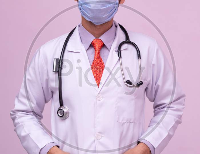 Doctor Wearing Medical Mask.  Standing With Both Hands In Pocket On Isolated Background.