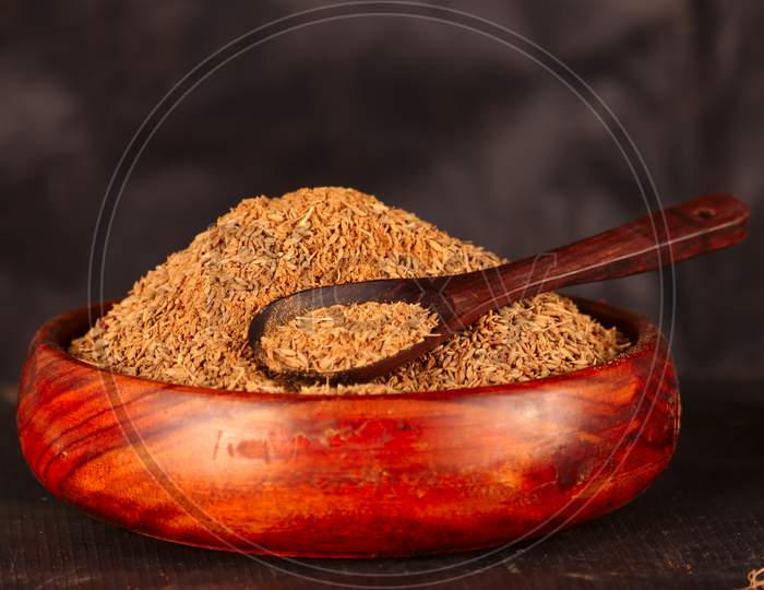Cumin Seeds Isolated On Black Background,Wooden Bowl Blurry Background Selective Focus On Small Cumin Seeds,Wooden Spoon On Carvi