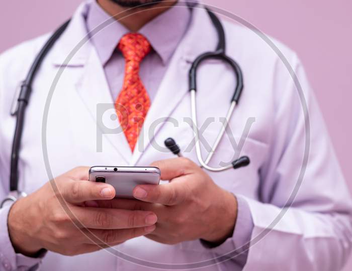 Medical App. Smartphone In Hands Of  Male Doctor On Isolated Background.