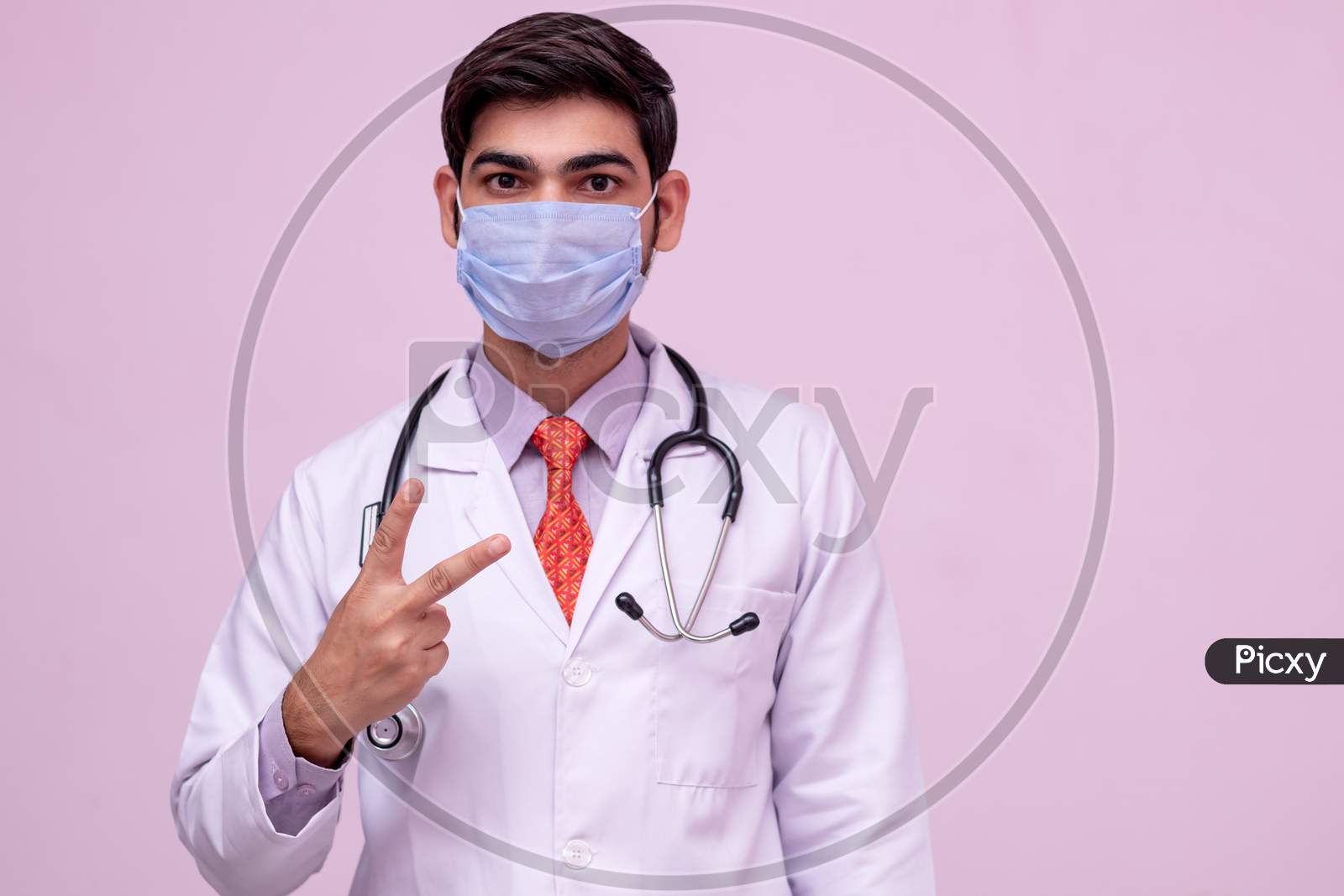 Doctor Wearing Medical Mask Showing Victory With Hand On Isolated Background.